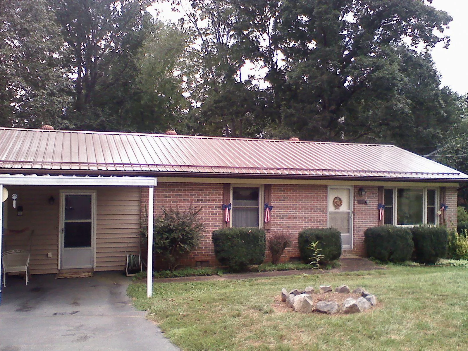 Bronze metal roof and carport on a brick ranch home — Roof Repair work by our crew in Eddyville