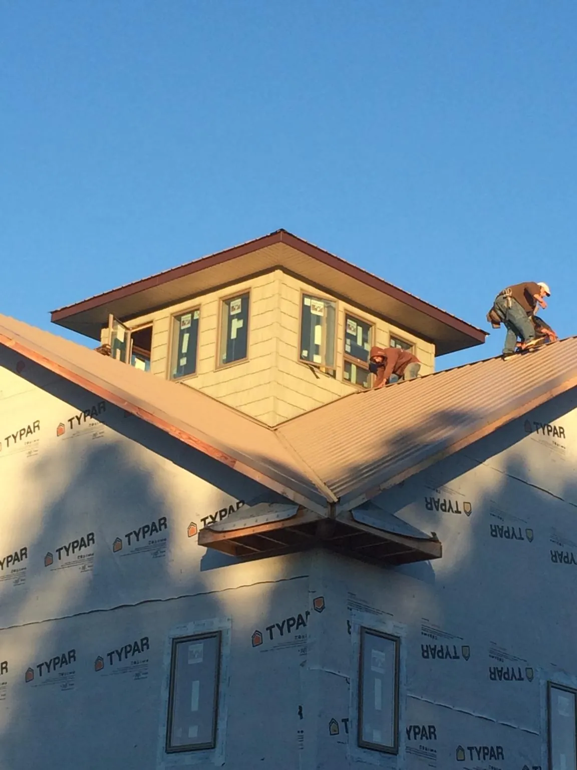 Roofers working around a rooftop cupola on a new metal roof at sunset — Roof Waterproofing in Eddyville by Roofing Brothers